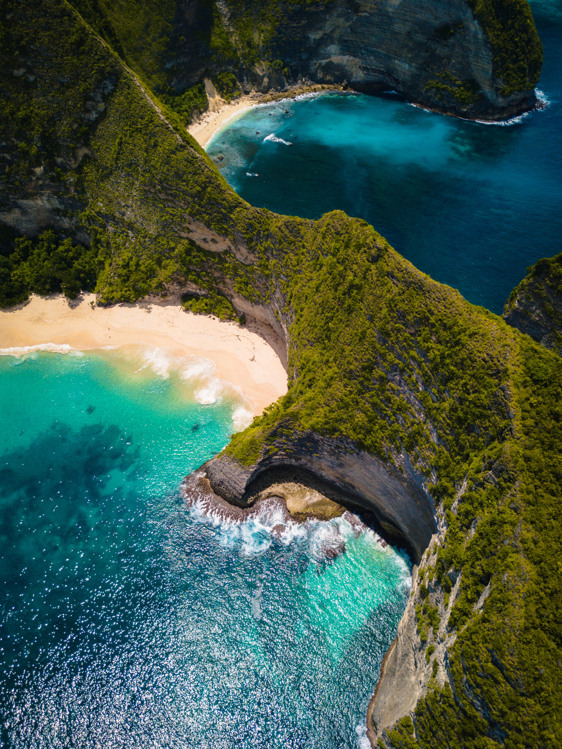 Aerial shot of the ocean surrounded by beautiful cliffs covered in greens